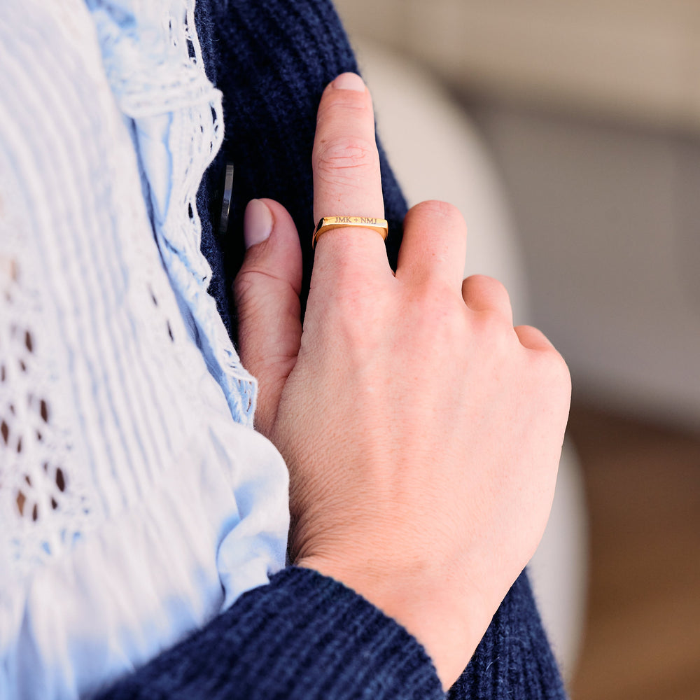 Engravable flat-top band ring with custom initials engraved on the face, worn by a model.