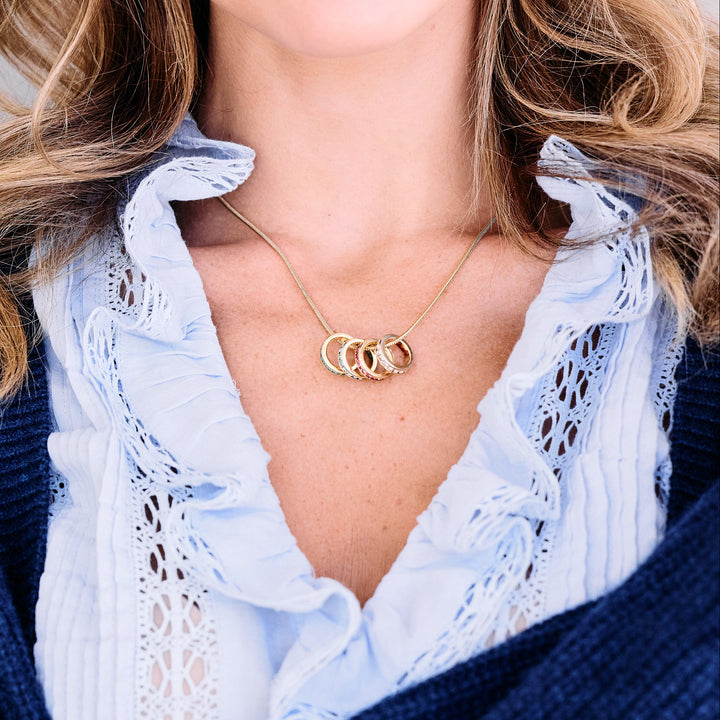 Birthstone eternity charm necklace with five crystal-studded circular charms on a chain, worn by a model.