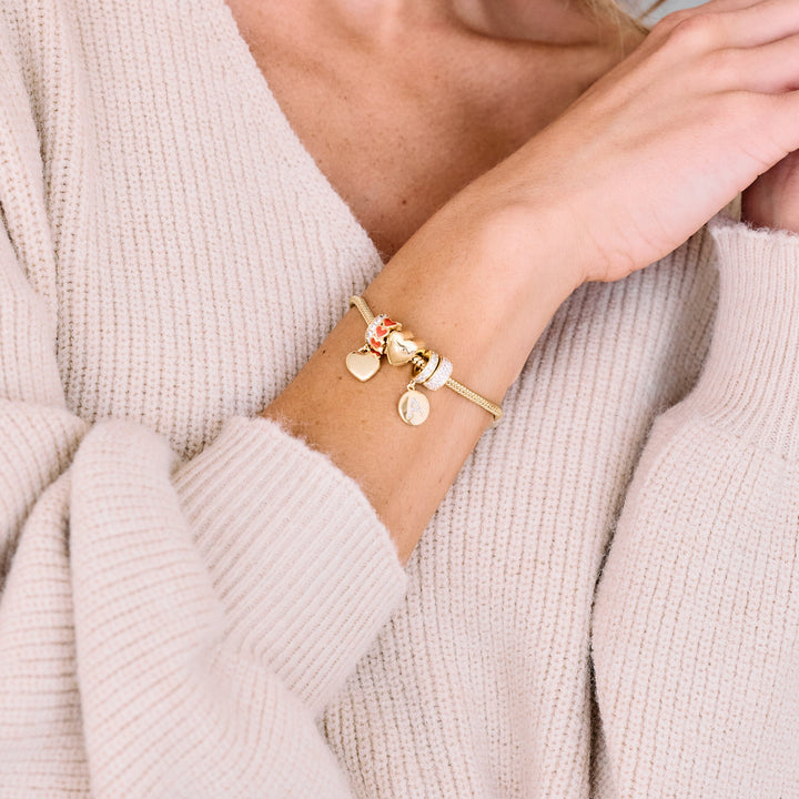 Charm bracelet with a butterfly dangle charm and crystal-set bead, styled with heart charms and enamel accents, worn by a model.