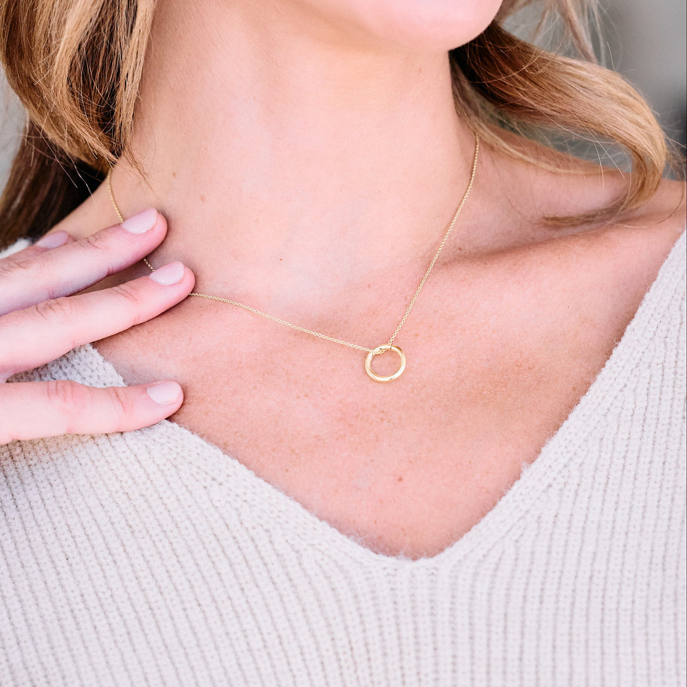 Circle pendant necklace with a polished open ring clasp on a delicate chain, worn by a model.