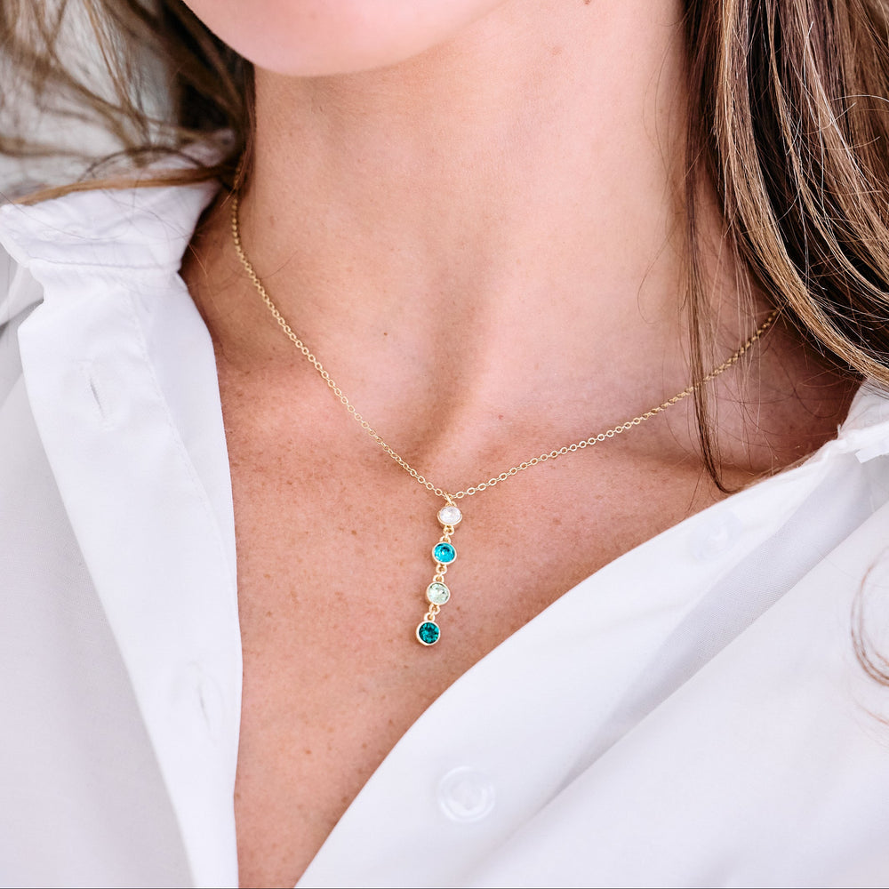 gold rolo necklace with birthstones hanging on women wearing white shirt.
