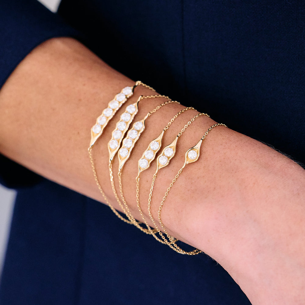 Set of stacked Pea and the Pod bracelets with eye-shaped moissanite stations in varying stone counts, worn by a model.