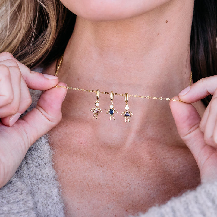 Build Your Own Child Charm Necklace with three birthstone figure charms clipped onto a chain, worn by a model.
