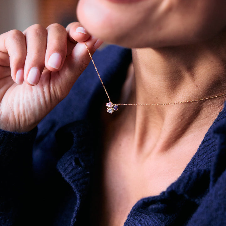 Birthstone Heart Love Necklace with four heart-cut multicolor stones in a clover-like cluster pendant, worn by a model.