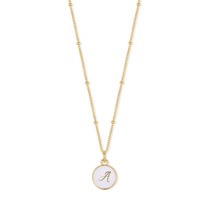 Initial pendant necklace with a round white enamel disc engraved with a script initial, on a chain with evenly spaced beads.